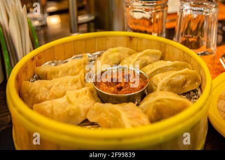 Selektive Konzentration von traditionellen tibetischen Momos in servierten Bamboo Dampfgarern mit Tomatenchutney oder Dip. Stockfoto