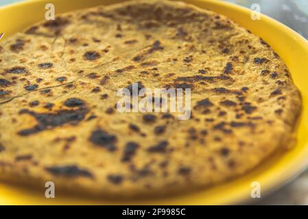 Selektive Fokusansicht des traditionellen indischen Essens Aloo Paratha oder gefülltes Kartoffelflachbrot auf buntem oder hölzernen Hintergrund. Das ist ein beliebtes Frühstück Stockfoto