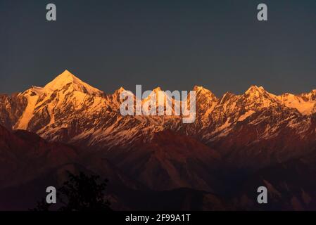 Panoramablick während des Sonnenuntergangs über schneebedeckten Panchchuli-Gipfeln fällt in großen Himalaya-Bergkette aus dem kleinen Weiler Munsiyari, Kumaon Region, Ut Stockfoto