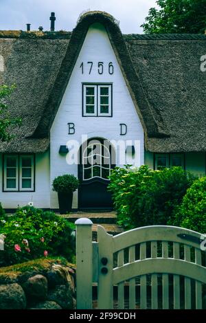 Ein Gartentor in einer Steinmauer und eine Haustür eines Hauses aus dem Jahr 1756 auf Sylt. Stockfoto