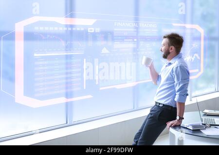 Junger Geschäftsmann in der Nähe des virtuellen Bildschirms im modernen Büro Stockfoto