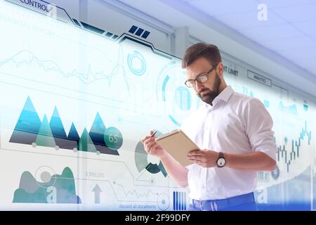 Junger Geschäftsmann in der Nähe des virtuellen Bildschirms im modernen Büro Stockfoto