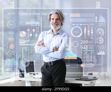 Senior Geschäftsmann in der Nähe von virtuellen Bildschirm in modernen Büro Stockfoto