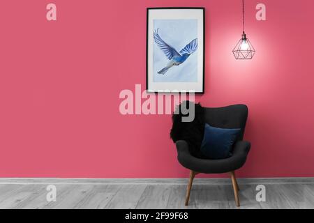 Glühende Lampe mit Sessel und Bild in Farbe Wand Zimmer Stockfoto