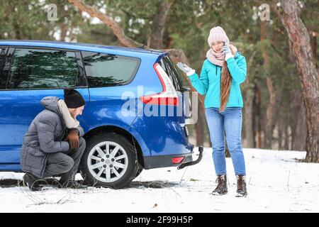 Junges Paar in der Nähe eines kaputten Autos am Wintertag Stockfoto