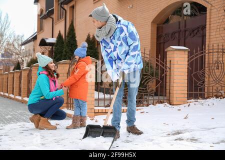 Die Familie entfernt Schnee im Freien am Wintertag Stockfoto