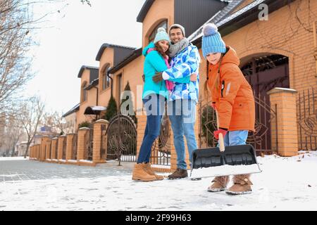 Die Familie entfernt Schnee im Freien am Wintertag Stockfoto