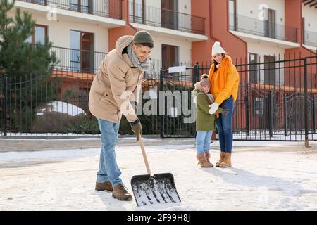 Die Familie entfernt Schnee im Freien am Wintertag Stockfoto