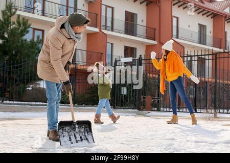 Die Familie entfernt Schnee im Freien am Wintertag Stockfoto