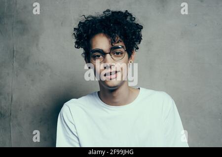 Mann mit lockigen Haaren trägt Brille Emotionen weißes T-Shirt Studio Stockfoto