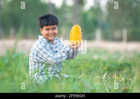 Ein Junge mit einer Melone im Feld Qualitätsauswahl für Verbraucher, Kid Lächeln mit Melone auf dem Bauernhof Stockfoto