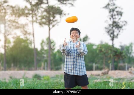 Ein Junge mit einer Melone im Feld Qualitätsauswahl für Verbraucher, Kid Lächeln mit Melone auf dem Bauernhof Stockfoto