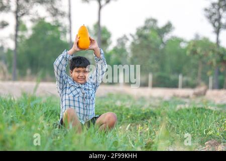 Ein Junge mit einer Melone im Feld Qualitätsauswahl für Verbraucher, Kid Lächeln mit Melone auf dem Bauernhof Stockfoto