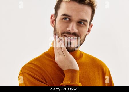 Fröhlicher Mann, der die Hand auf dem Gesicht hält, beschnittene Ansicht, Glamour-Nahaufnahme Stockfoto