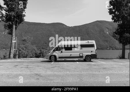 Wohnmobil / Van „Vantourer Black and White“ vor Spektakuläre Umgebung eines Sees und einige Berge vom See como Stockfoto