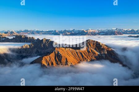 Wilde Berglandschaft über Wolkendecke bei Sonnenuntergang in den Allgäuer Alpen. Im Vordergrund Lachenspitze und Rote Spitze bei Tannheim, im Hintergrund Lechtaler Alpen. Tirol, Österreich, Europa Stockfoto