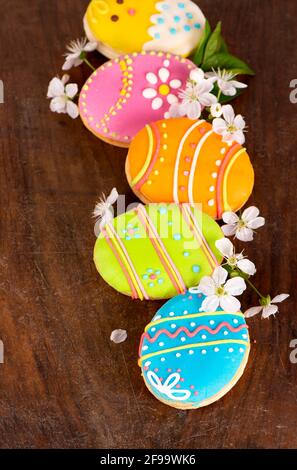 Lebkuchenkeks in Form von farbigen Eiern auf dunklem Holzhintergrund. Frohe Ostern Karte. Helle Kekse. Leckereien für Kinder. Platz zum Kopieren Stockfoto