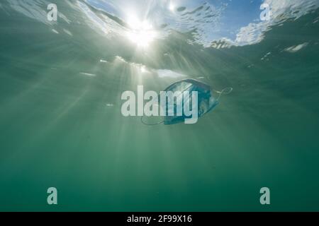 Schwimmende Facemask unter Wasser verursacht Plastikverschmutzung Stockfoto