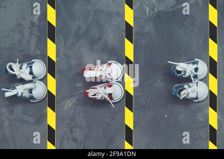 Konzept der sozialen Distanzierung. Turnschuhe und Warnband auf dem Asphalt-Hintergrund. Speicherplatz kopieren. Halten Sie Abstand, um die Ausbreitung des Virus zu verhindern. Neu Stockfoto