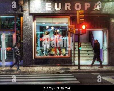 Straßenszene mit zwei Passanten, einer roten Ampel und einem Geschäft mit der Aufschrift Europa Stockfoto