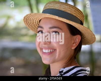 Attraktive fröhliche junge mexikanische Öko-Farm Frau und trägt einen klassischen Panama Strohhut und lächelt mit ihren schönen langen Wimpern für die Kamera. Stockfoto