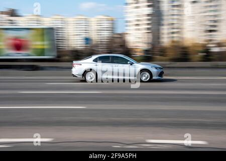 Ukraine, Kiew - 4. April 2021: Silbernes Toyota Camry Auto bewegt sich auf der Straße. Redaktionell Stockfoto