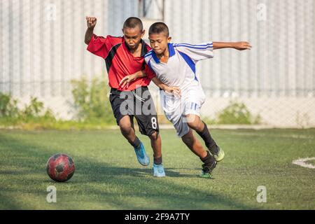 Running Fußball-Fußballspieler. Fußballspieler treten Football Match Spiel. Junge Fußballspieler laufen nach dem Ball. Lokales Thailand Stockfoto