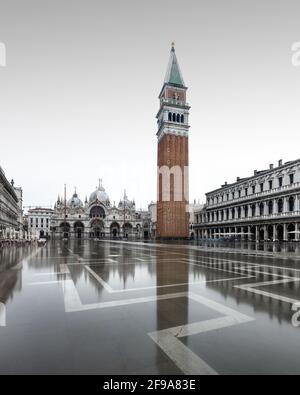 In den kühleren Wintermonaten überflutet die berühmte Flut, auch bekannt als Aqua Alta, regelmäßig den Markusplatz in Venedig und bietet wunderschöne Spiegelungen des campanile und der umliegenden Gebäude. Stockfoto