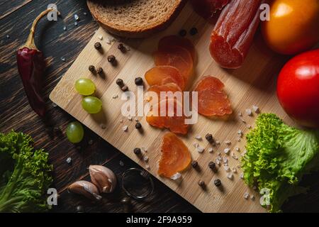 Geschnitten ruckig auf einem Brett. Gemüse, Brot und Fleisch auf dem Tisch. Komponenten eines Sandwiches. Stockfoto