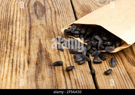 Schwarze, ungeschälte Sonnenblumenkerne in Basteltasche auf Holztisch. Studio Photo Stockfoto