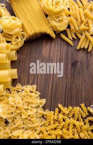 Verschiedene Arten von Pasta auf einem hölzernen Hintergrund. Farfalle, Fettuccine, Nudeln. Stockfoto