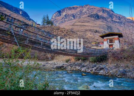 Die Tachogang Lhakhang-Brücke, die im Volksmund als Eiserne Kettenbrücke bekannt ist, überquert den Paro Chhu zum Dzong. Diese 600 Jahre alte Brücke wurde von Than gebaut Stockfoto