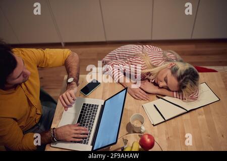 Junges erwachsenes kaukasisches Paar, das spät in der Nacht von zu Hause aus arbeitet. Burnout-Konzept Stockfoto