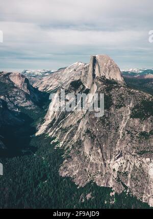 Wunderschöne Aussicht auf die verwinkelte Glacier Point Road mit dem berühmten Half Dome-Gipfel im goldenen Abendlicht bei Sonnenuntergang im Herbst, Yosemite National Park, Californi Stockfoto