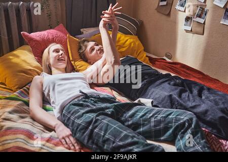 Junges Paar liegt auf dem Bett und hält die Hände sie entspannen Zusammen im Raum Stockfoto
