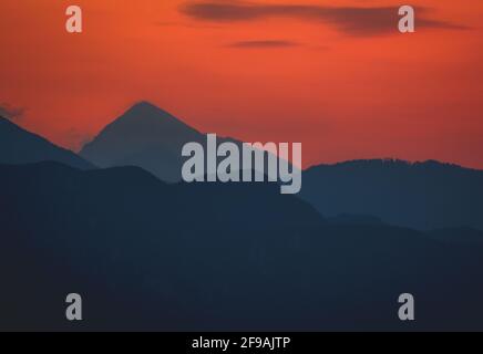 Die Sonne untergeht hinter der großen Silhoutte des Berges Stockfoto