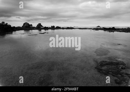 Schwarz-weißer Sonnenuntergang am strand von legon Pari in Sawarna Am späten Nachmittag Stockfoto