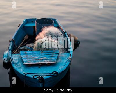 Typisches Fischerboot mit Netzen und hölzernen Rudern vor Anker Ein Pier Stockfoto