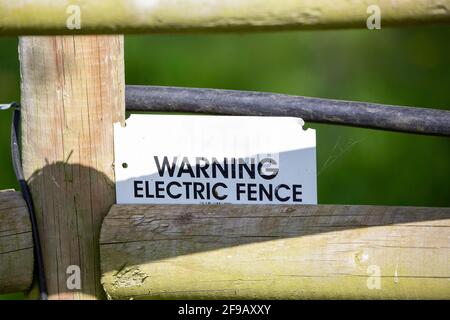 Ein Warnschild an einem elektrischen Zaun auf Ackerland Stockfoto