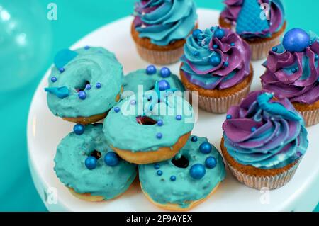 Muffins und Mini-Donuts. Backen für eine Kinderparty mit maritimem Thema. Desserts in Blau Stockfoto