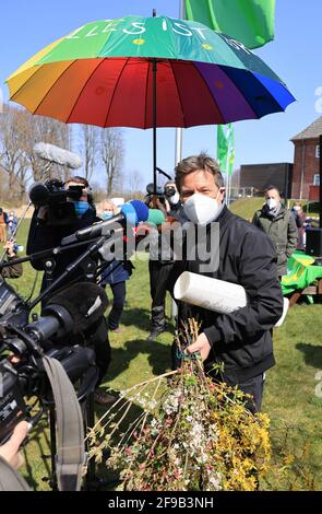 Steinbergkirche, Deutschland. April 2021. Robert Habeck, Bundesvorsitzender von Bündnis 90/die Grünen, wird bei einer Mitgliederversammlung der Grünen nach seiner Wahl zum Direktkandidaten für die Bundestagswahl 2021 mit einem bunten Regenschirm, Blumen und einem Bild überreicht. Die Grünen der Stadt Flensburg und des Landkreises Schleswig-Flensburg wählten bei der Veranstaltung in der Steinbergkirche ihren Direktkandidaten für die Bundestagswahl im September. Der einzige Kandidat war Parteiführer Habeck. Quelle: Christian Charisius/dpa/Alamy Live News Stockfoto