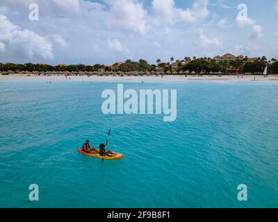 Aruba Karibik Paar Männer und Frau mittleren Alters in einem Kajak im blauen Meer am Strand mit Palmen Bäume auf Aruba Stockfoto