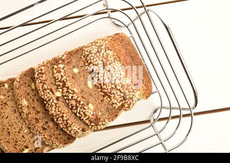 Ein paar frische, duftende, leckere, Sesambrote in einem Korbkorb aus Metalldraht, aus nächster Nähe, auf einem bemalten Tisch aus Naturholz. Stockfoto