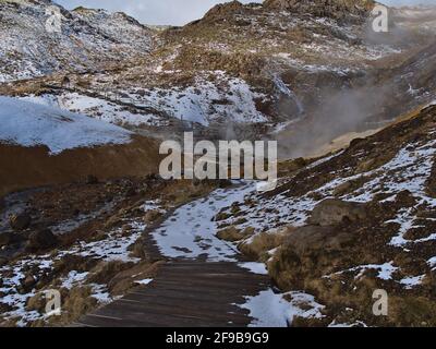 Hölzerner Fußweg durch das geothermische Gebiet Seltún, Teil des vulkanischen Systems Krýsuvík, mit heißen Quellen, Fumarolen und Schlammtöpfen in Island. Stockfoto