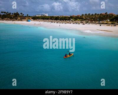 Aruba Karibik Paar Männer und Frau mittleren Alters in einem Kajak im blauen Meer am Strand mit Palmen Bäume auf Aruba Stockfoto