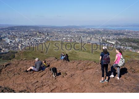 Edinburgh, Schottland, Großbritannien. April 2021. Am ersten vollen Wochenende, an dem Reisebeschränkungen in ganz Schottland aufgehoben wurden, strömen die Menschen zu den üblichen Besucherherden, um die Sonne und die Natur im Holyrood Park zu genießen. Auf dem Gipfel von Arthur's Seat. Kredit: Craig Brown/Alamy Live Nachrichten Stockfoto