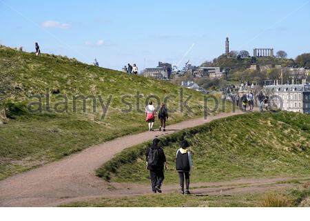 Edinburgh, Schottland, Großbritannien. April 2021. Am ersten vollen Wochenende, an dem Reisebeschränkungen in ganz Schottland aufgehoben wurden, strömen die Menschen zu den üblichen Besucherherden, um die Sonne und die Natur im Holyrood Park zu genießen. Auf den flachen Wegen rund um den Holyrood Park mit Blick auf Calton Hill. Kredit: Craig Brown/Alamy Live Nachrichten Stockfoto