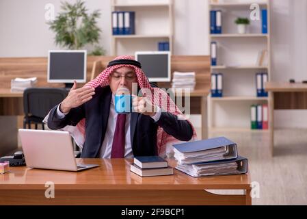 Gealterter arabischer Angestellter, der während der Pause Kaffee trinkt Stockfoto