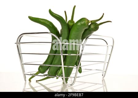 Mehrere Schoten reifer organischer, würziger grüner Paprika in einem Korb aus Draht, Nahaufnahme, auf weißem Hintergrund. Stockfoto