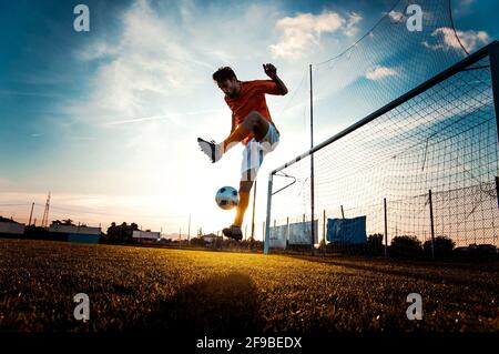 Fußballspieler in Aktion auf dem Fußballstadion - man Fußball bei Sonnenuntergang spielen - Fußball- und Sportmeisterschaftskonzept Stockfoto